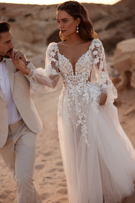 Robe de mariée Alia, avec un corset ajusté en dentelle, des fleurs en relief et un décolleté en V plongeant.