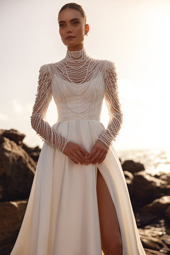 Blouse de mariée Alya à longues manches ornées de perles, portée avec une jupe à fente haute.
