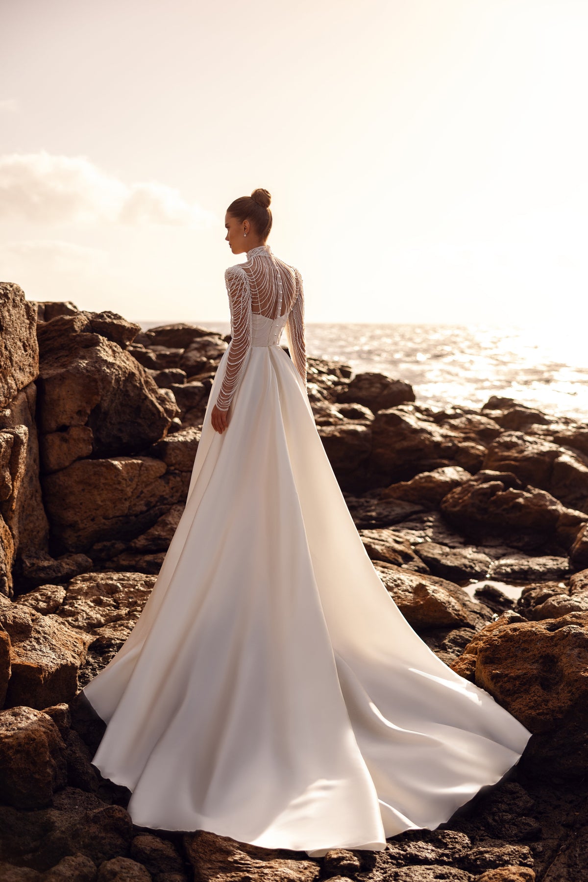 Blouse de mariée Alya à longues manches ornées de perles, présentée avec une traîne.