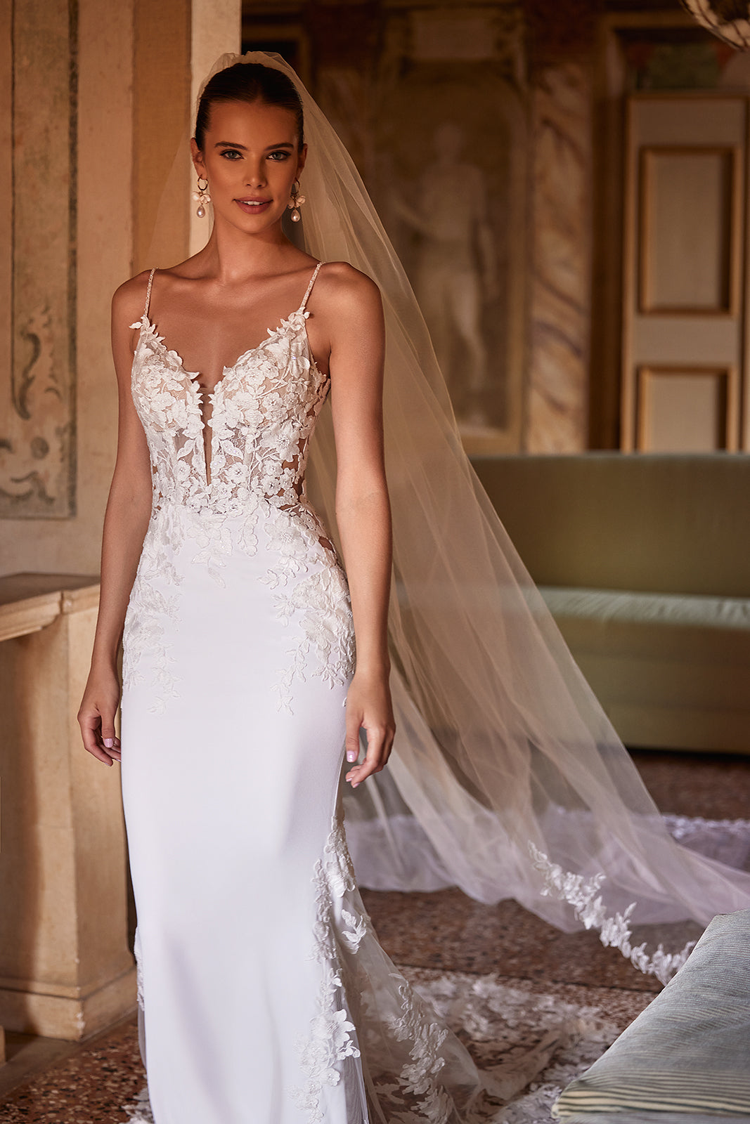 Voile de mariée long et classique Apolonia, bordé de dentelle florale et fixé par un peigne, de l’atelier DAMA Couture — vue de face.
