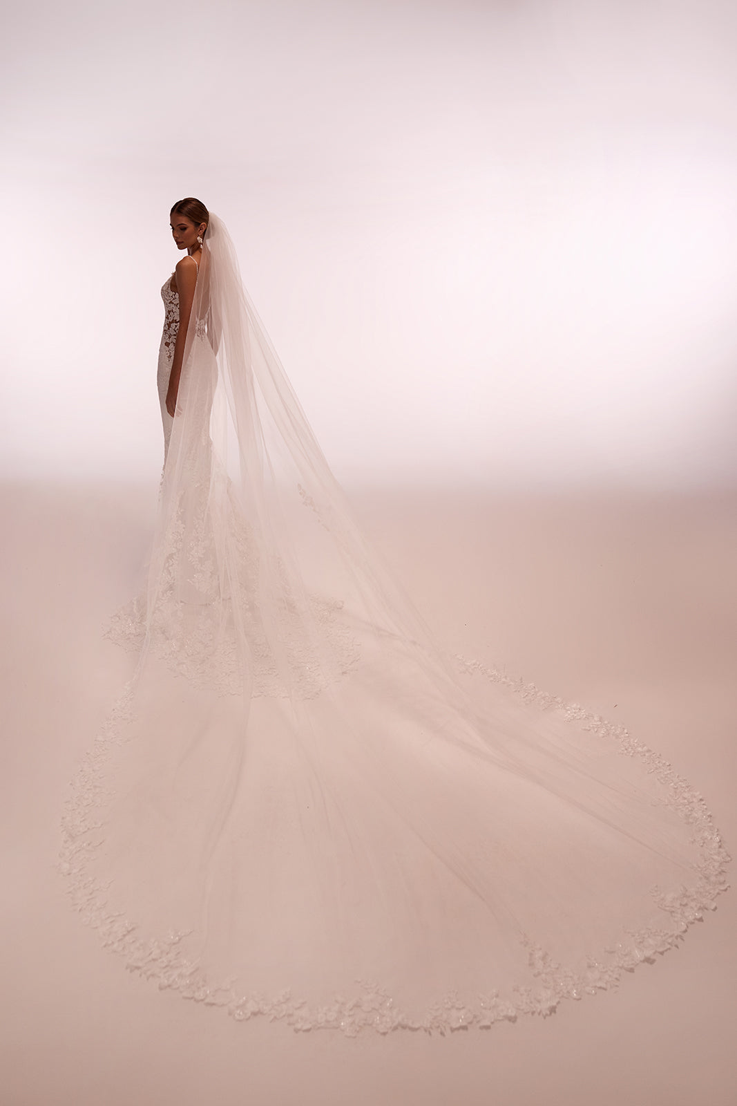 Voile de mariée long et classique Apolonia, bordé de dentelle florale et fixé par un peigne, de l’atelier DAMA Couture — vue de dos.