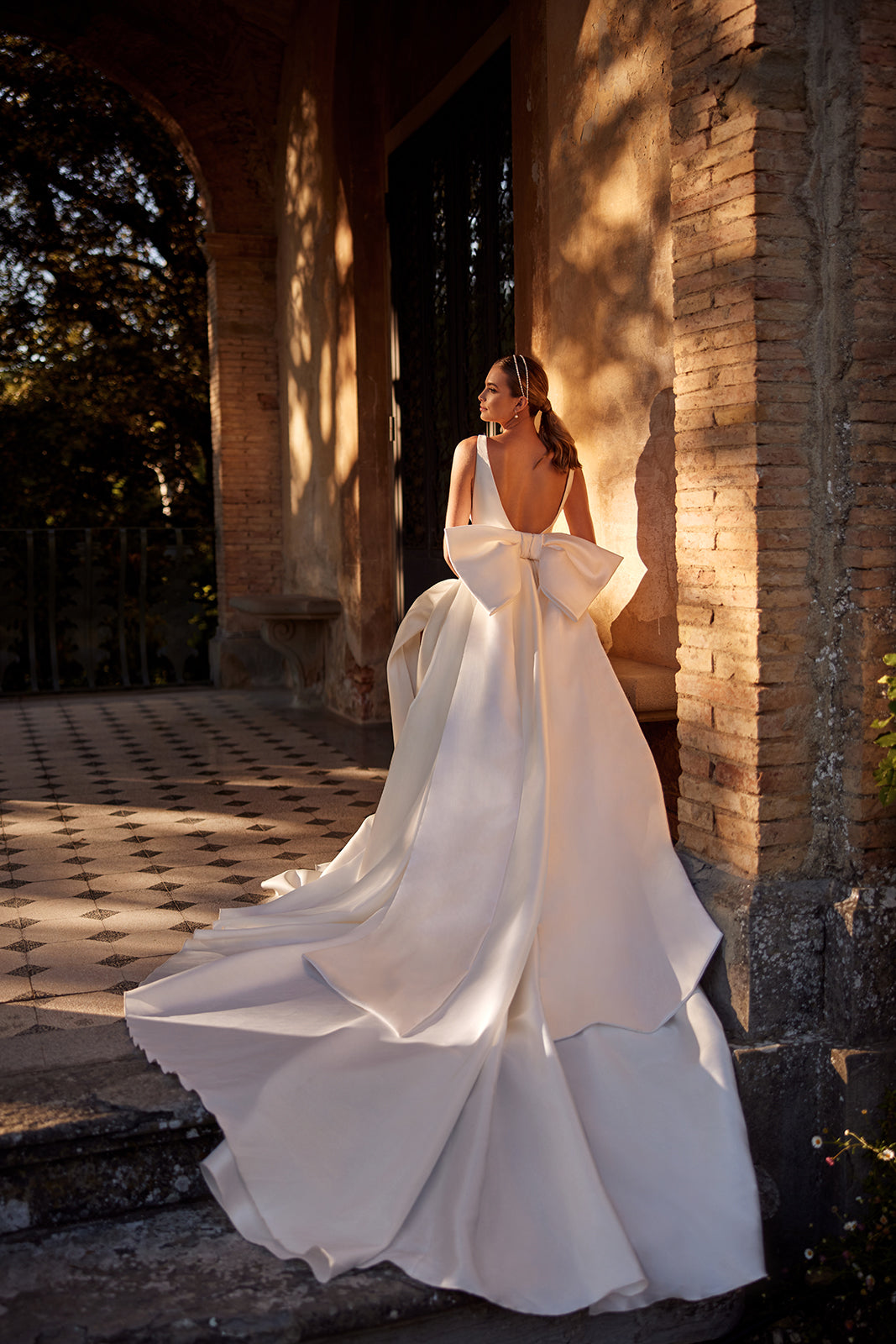 Robe de mariée classique Margo avec traîne à nœud, DAMA Couture — vue de dos, photo de campagne.