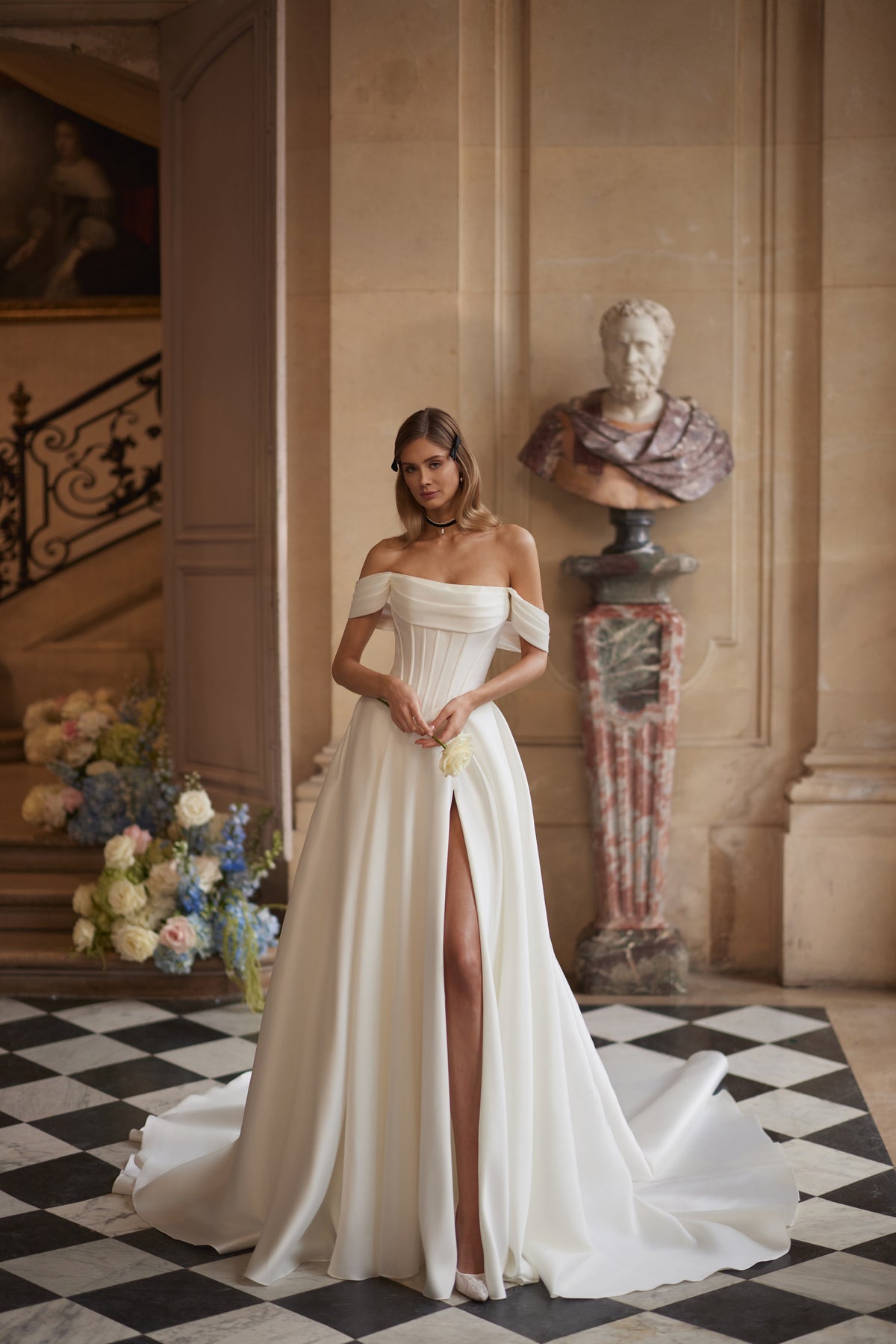 Robe de mariée Alienor, avec des manches drapées laissant les épaules dénudées et une jupe épurée en satin — collection Something Blue 2027, DAMA Couture.