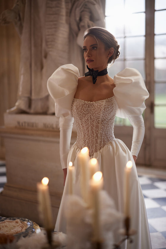Robe de mariée trapèze Aliette, avec un corset orné de cristaux et des manches volumineuses.