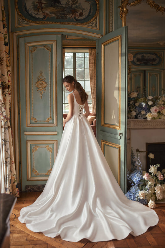 Robe de mariée trapèze Aretuza, avec un décolleté carré épuré, de fines bretelles et une jupe ample en satin.