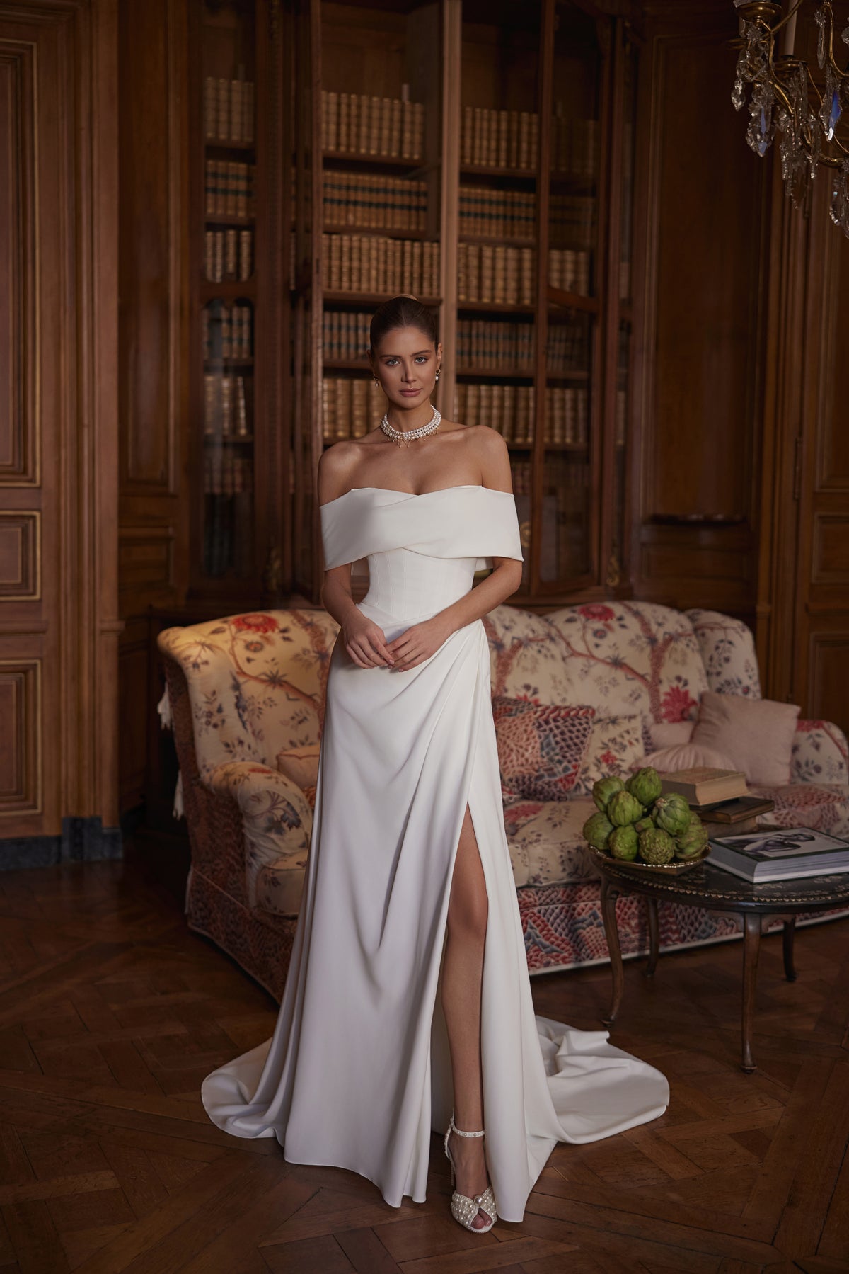 Robe de mariée trapèze Calliope, avec un large décolleté aux épaules dénudées et une jupe épurée en satin avec une fente.