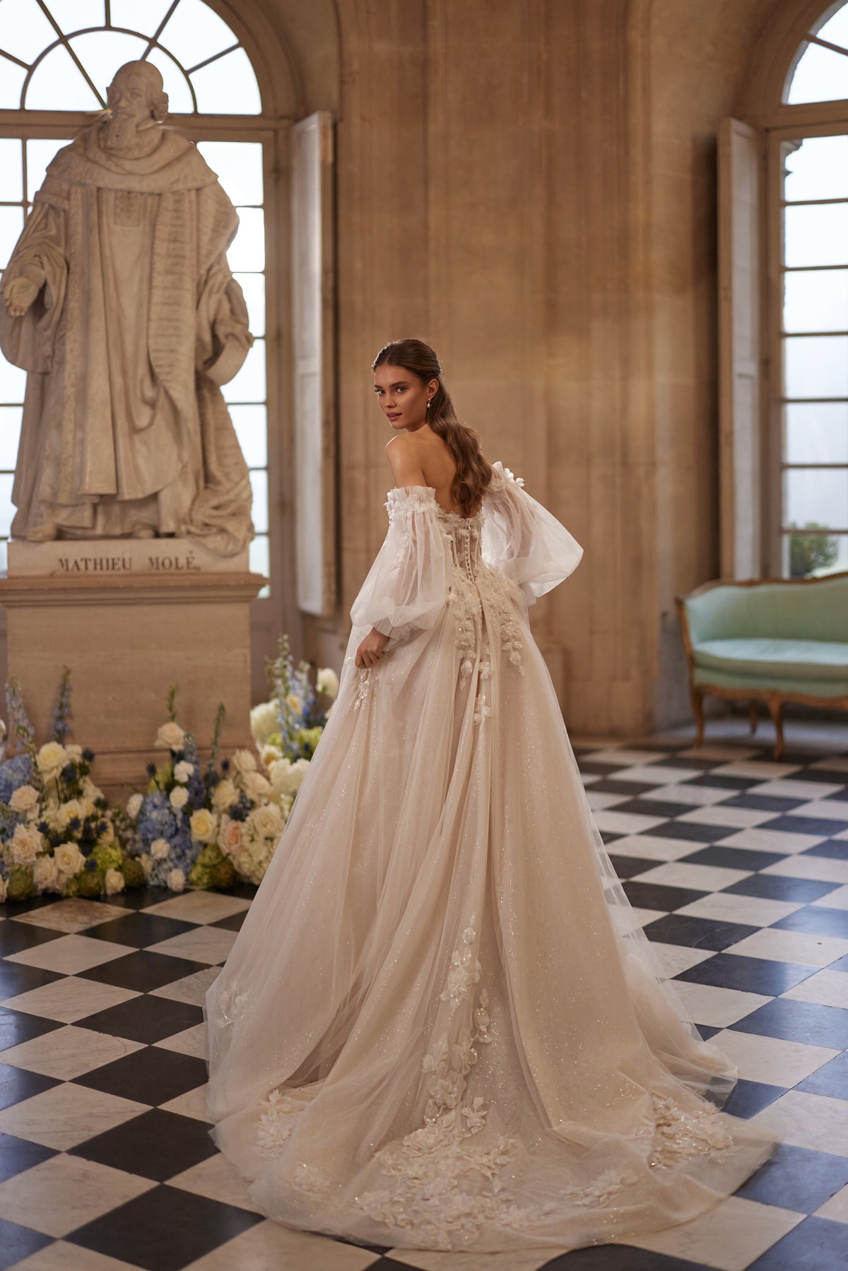 Robe de mariée Celestine, avec un décolleté ouvert, des manches légères laissant les épaules dénudées et des fleurs en relief.