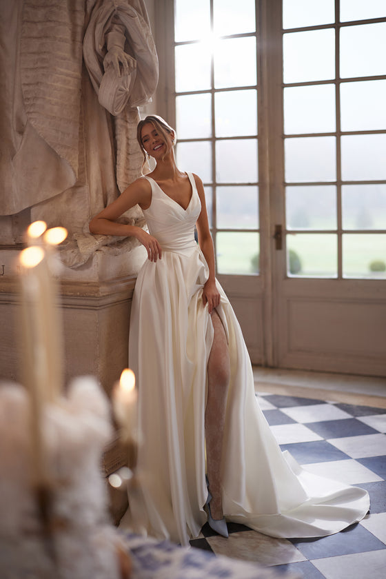 Robe de mariée trapèze Elvira, avec un décolleté en V ouvert et une jupe drapée épurée avec une fente haute.