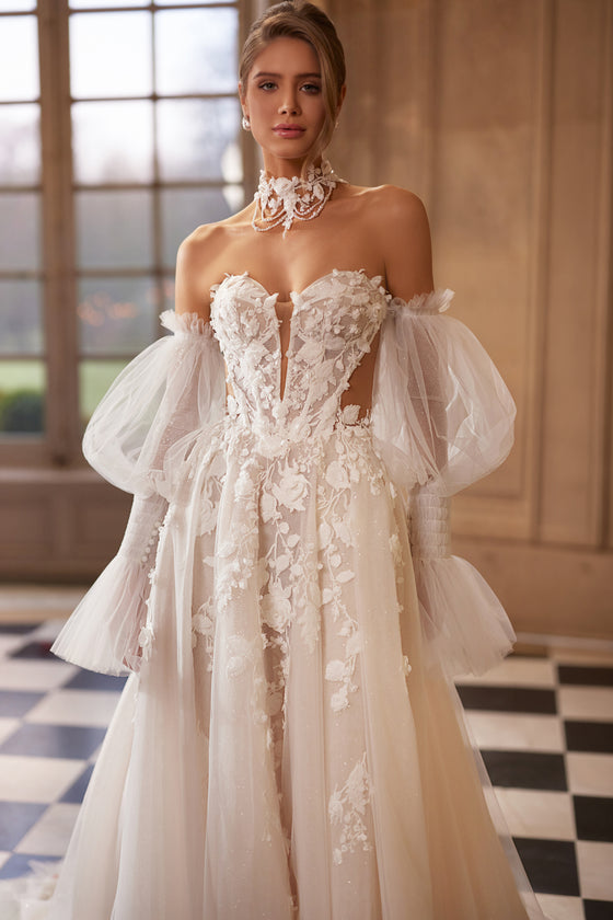 Robe de mariée trapèze Estella, avec un corset à fleurs en relief et des manches volumineuses laissant les épaules dénudées.