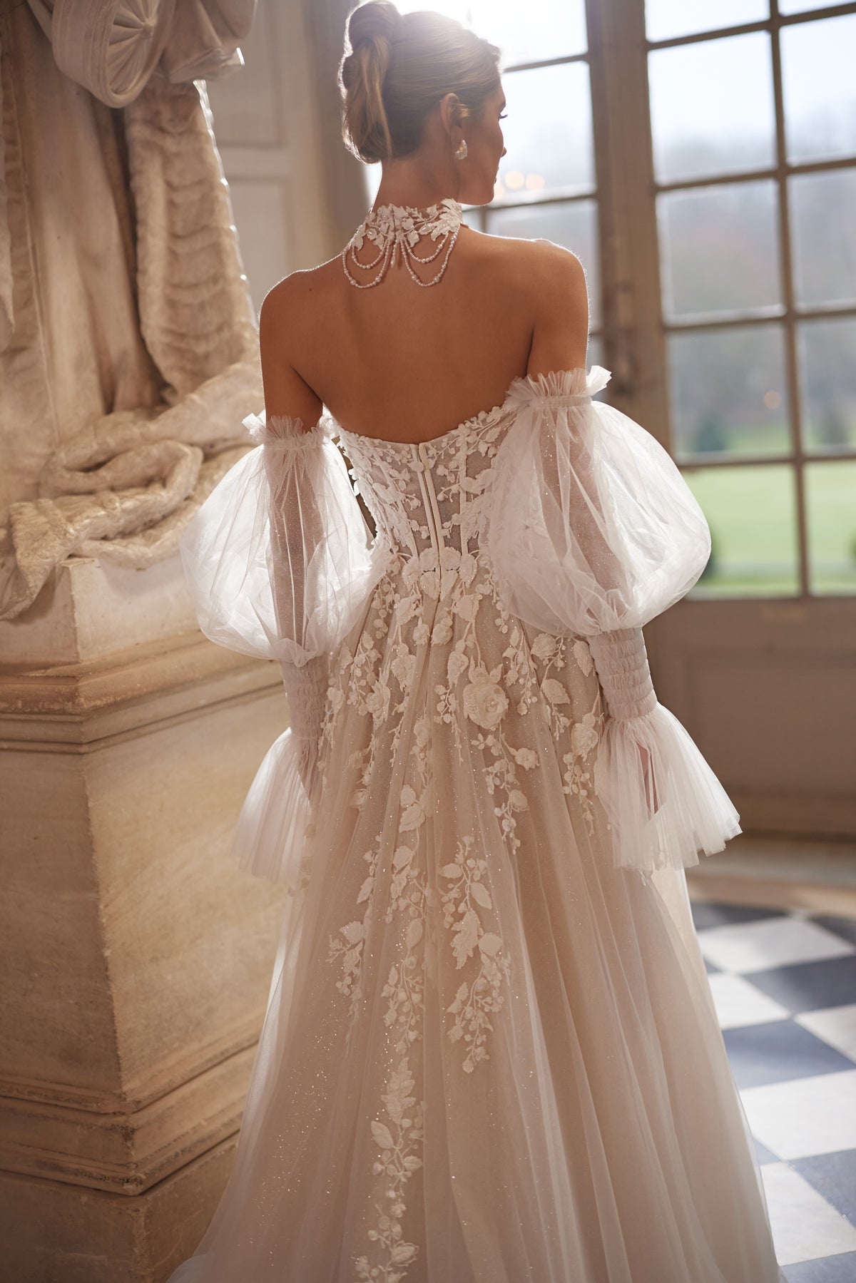 Robe de mariée Estella, avec un corset à fleurs en relief et des manches volumineuses laissant les épaules dénudées.