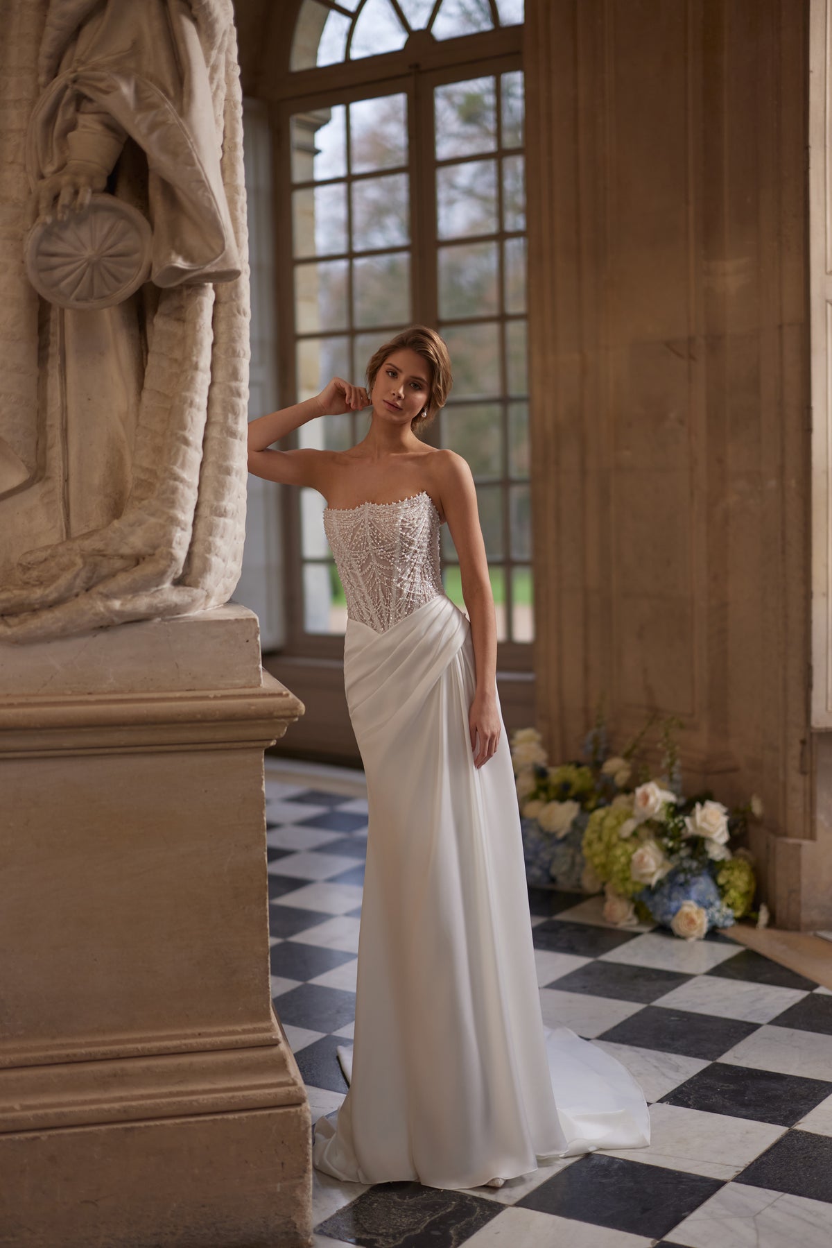 Robe de mariée sirène Greta, avec un corset sans bretelles richement perlé et une jupe drapée en satin.