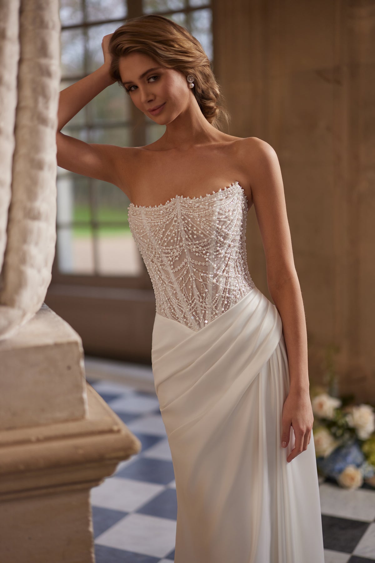 Robe de mariée Greta, avec un corset sans bretelles richement perlé et une jupe drapée en satin.