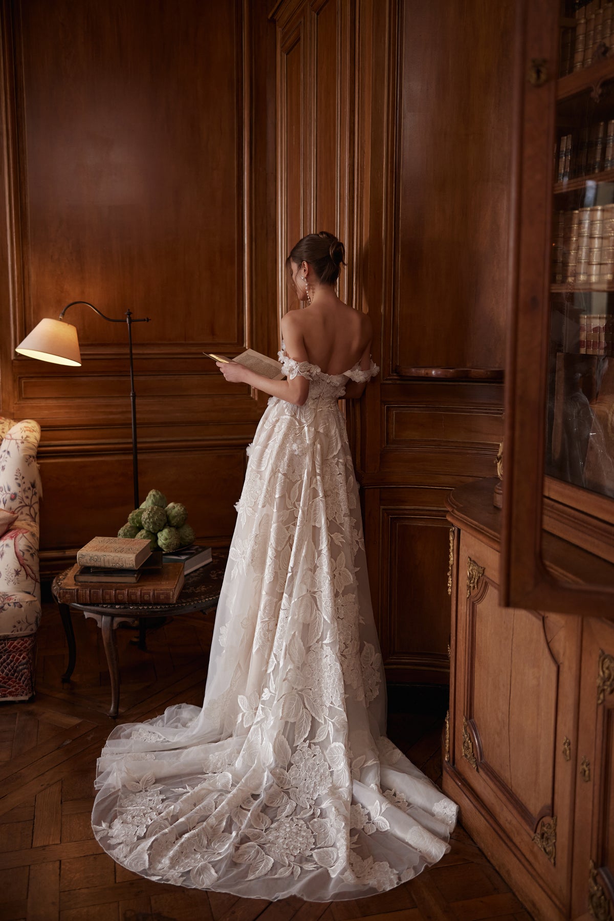 Robe de mariée trapèze Hydragenea, avec un décolleté plongeant et des bretelles florales retombant sur les bras.