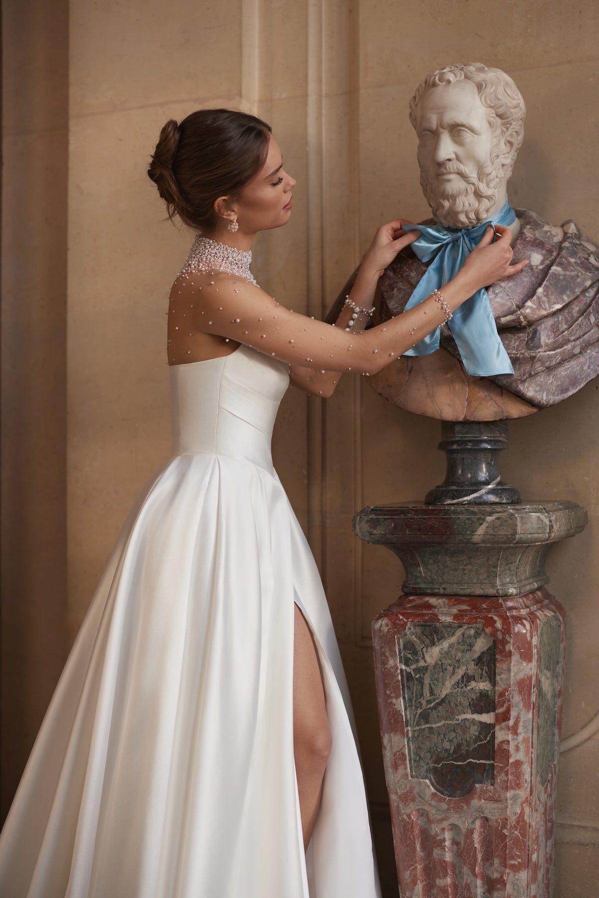 Robe de mariée Lucienne, avec un décolleté illusion orné de cristaux et une jupe drapée en satin avec une fente haute.