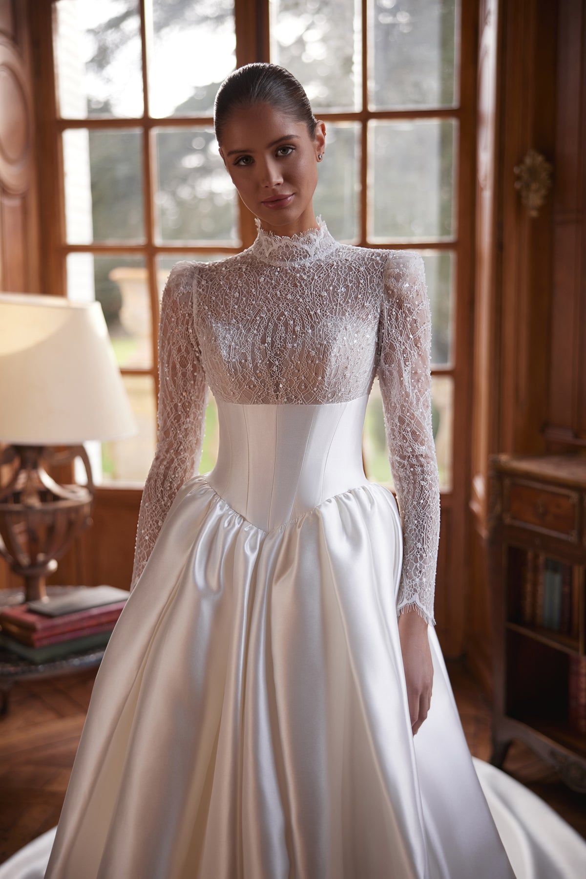 Robe de mariée trapèze Maristella, avec un corsage en dentelle à col montant, de longues manches et une jupe ample en satin.