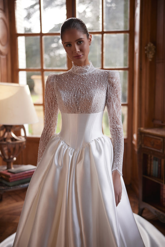 Robe de mariée trapèze Maristella, avec un corsage en dentelle à col montant, de longues manches et une jupe ample en satin.