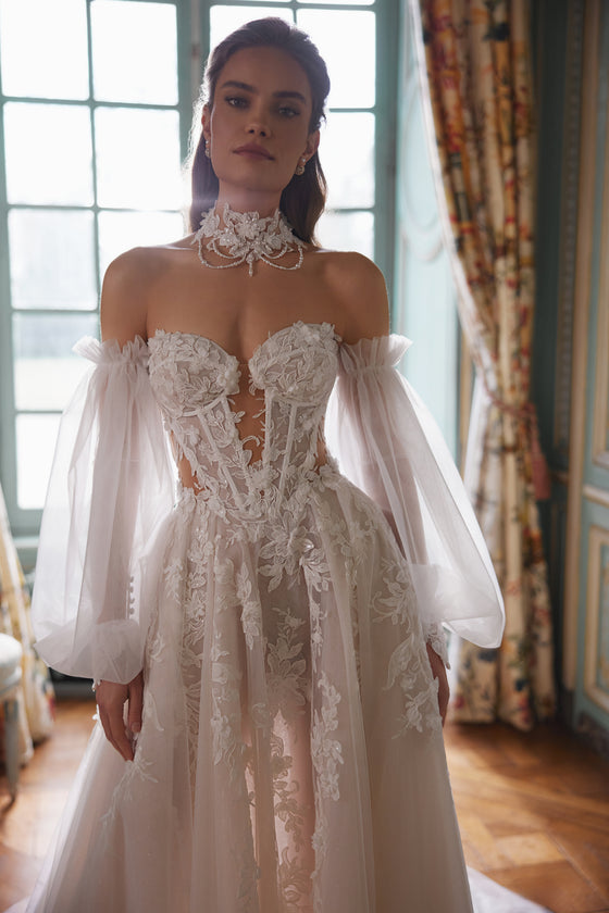 Robe de mariée trapèze Melusine, avec un corsage sans bretelles en dentelle à motifs végétaux et des manches amovibles en tulle.