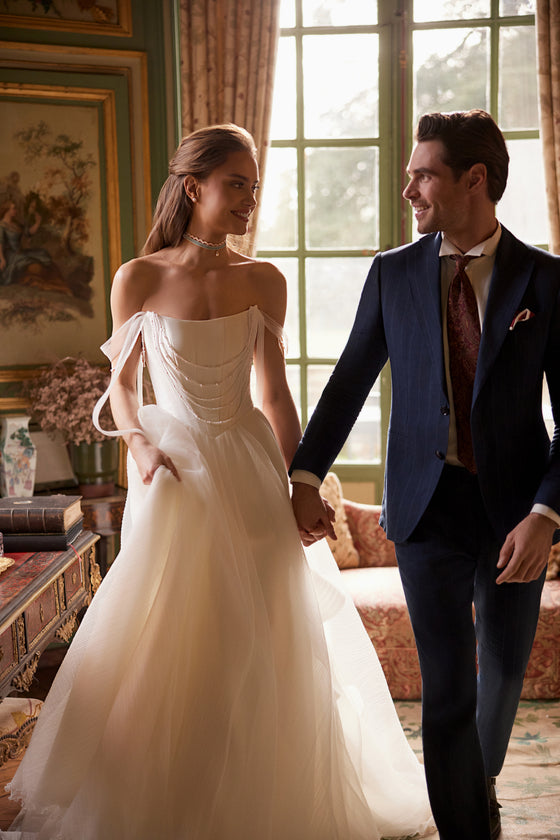 Robe de mariée trapèze Nerina, avec des détails évoquant des bijoux et des bretelles de tulle retombant sur les bras.