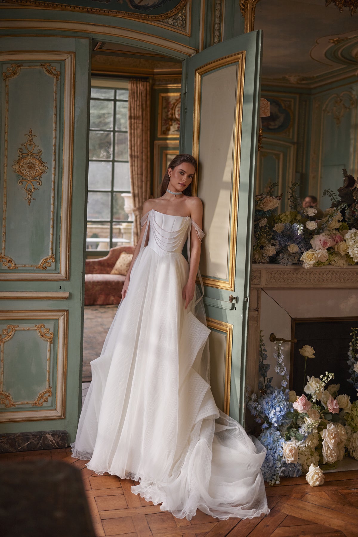 Robe de mariée trapèze Nerina, avec des détails évoquant des bijoux et des bretelles de tulle retombant sur les bras.