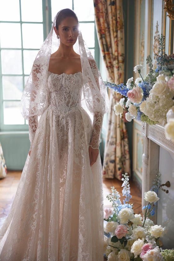 Robe de mariée trapèze Thetis, avec un corset transparent, des bretelles en dentelle et une somptueuse jupe en dentelle.