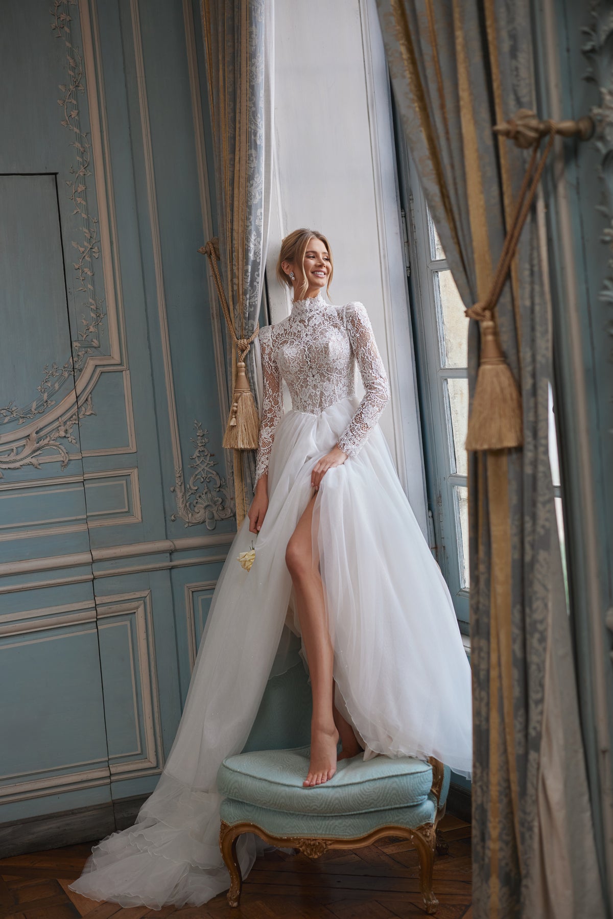 Robe de mariée trapèze Tonia, avec une encolure montante et de longues manches en dentelle transparente.