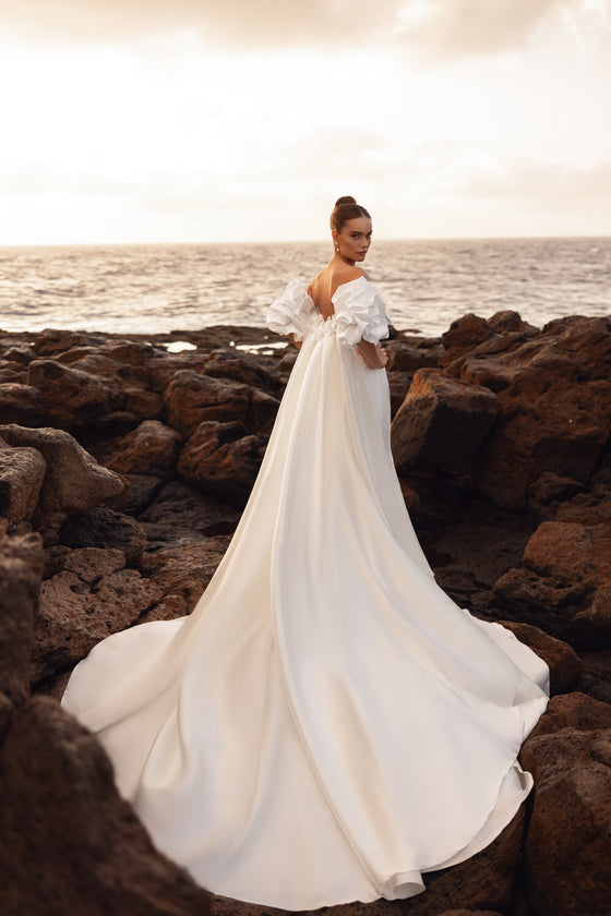 Robe de mariée dos nu, avec une traîne particulièrement longue.