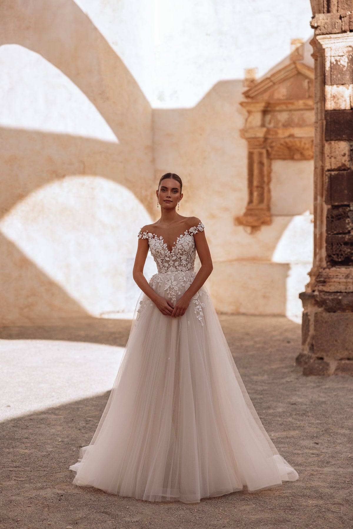 Robe de mariée Andrea, avec un dos nu, un corsage en dentelle et une traîne souple en tulle.