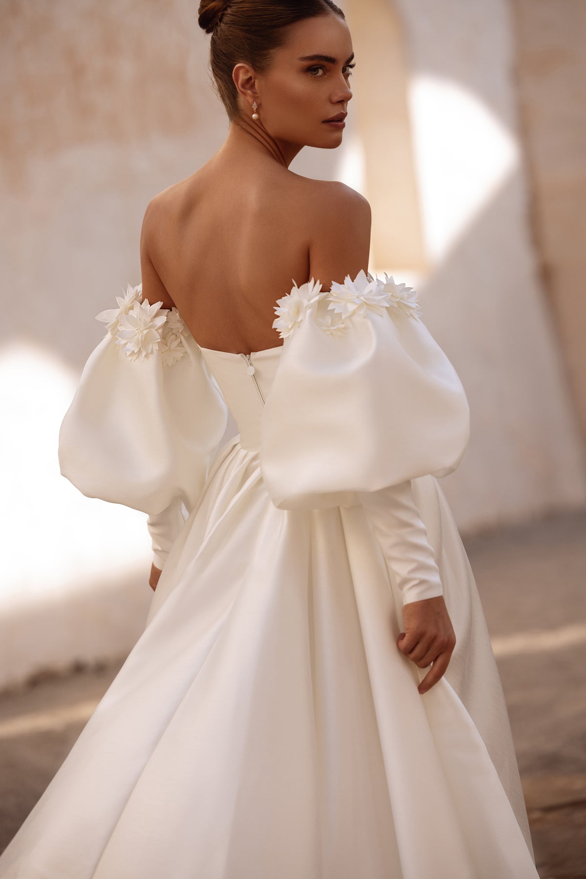 Robe de mariée Anika, avec de longues manches bouffantes et des détails floraux.