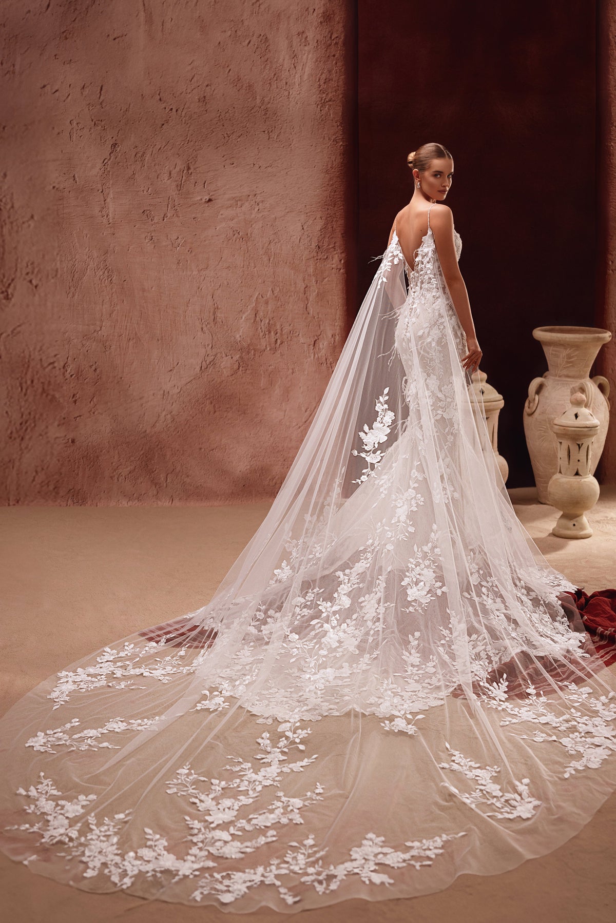 Robe de mariée Aspasia, avec une traîne en dentelle et une cape brodée de fleurs.
