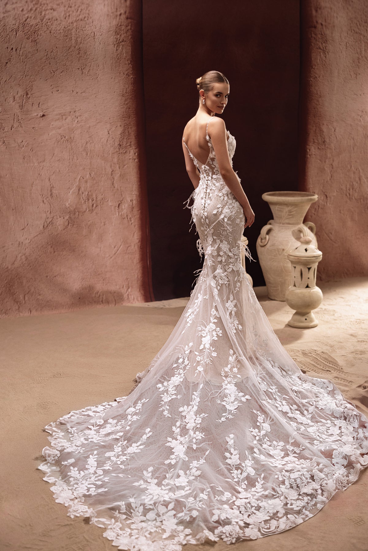 Robe de mariée Aspasia, avec un dos échancré et une traîne en dentelle brodée.