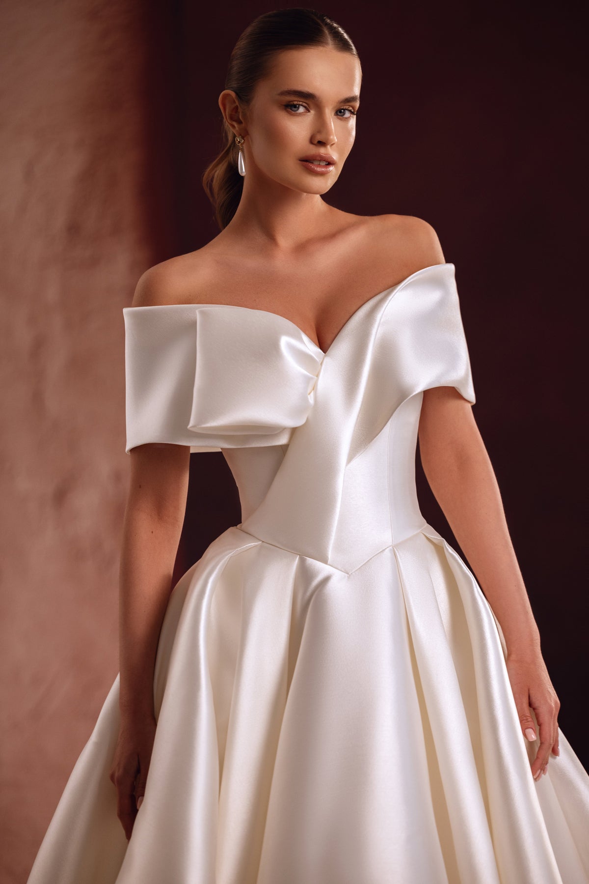 Gros plan sur la robe Avin, l’éclat du satin et son décolleté sculpté aux épaules dénudées.