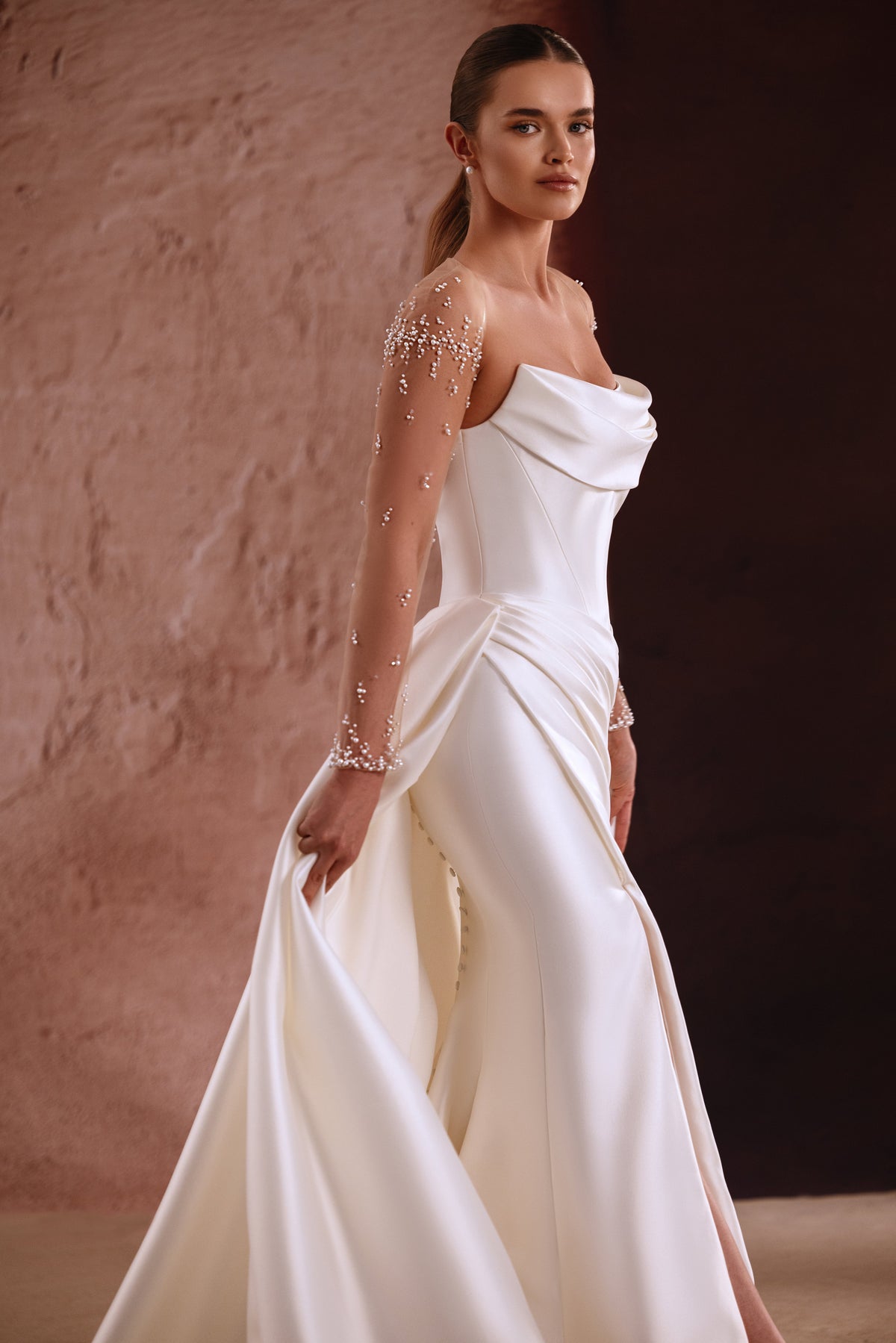 Robe de mariée Aylin, avec des manches transparentes ornées de perles et un décolleté drapé en satin.