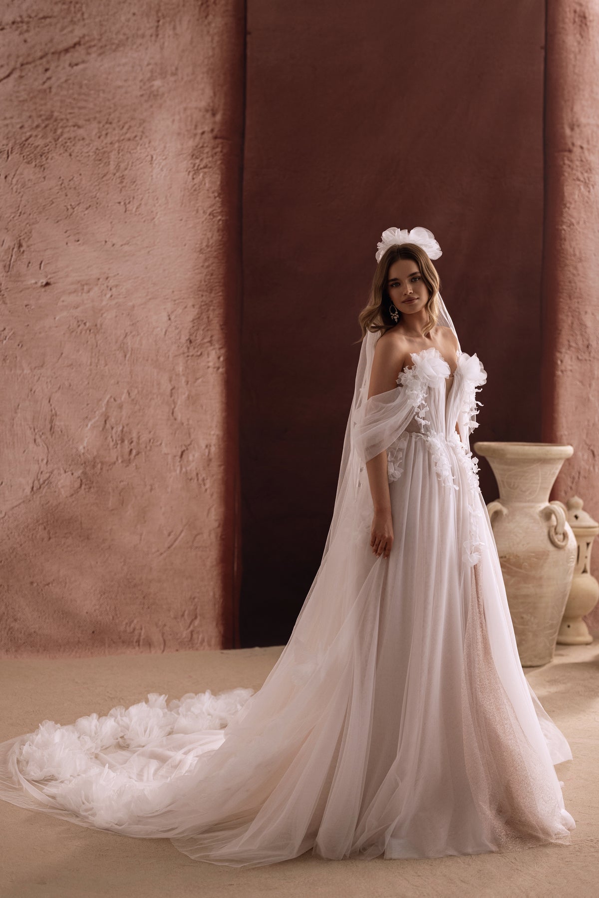 Dos de la robe Bella, avec une traîne en tulle ornée de fleurs en relief.