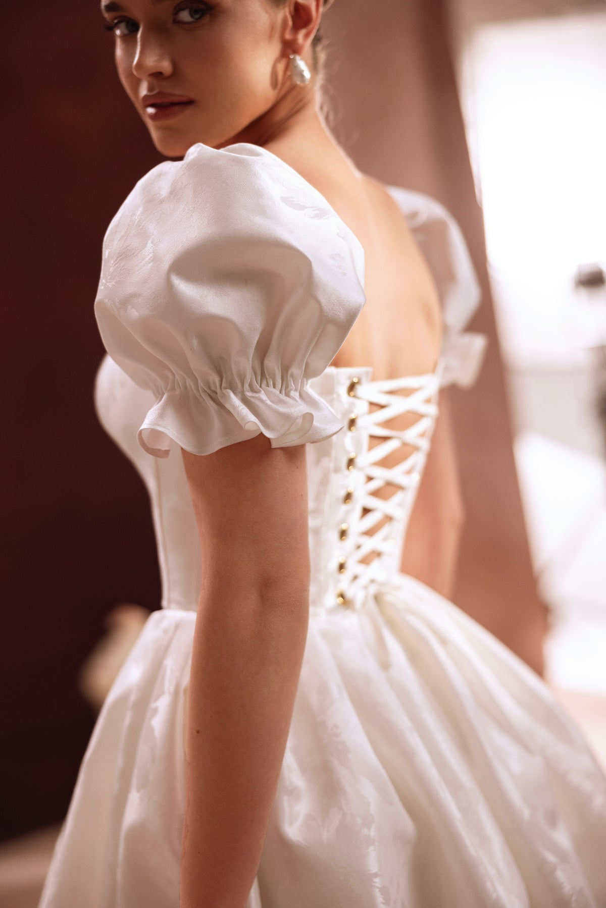 Robe de mariée courte Daphne, avec un décolleté cœur et des manches bouffantes.