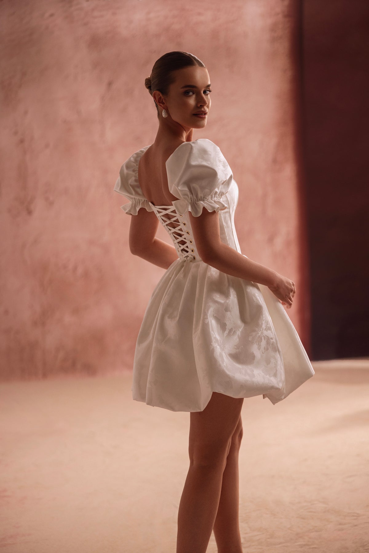 Mini-robe de mariée Daphne, avec un corset lacé dans le dos qui marque la taille et des manches bouffantes.