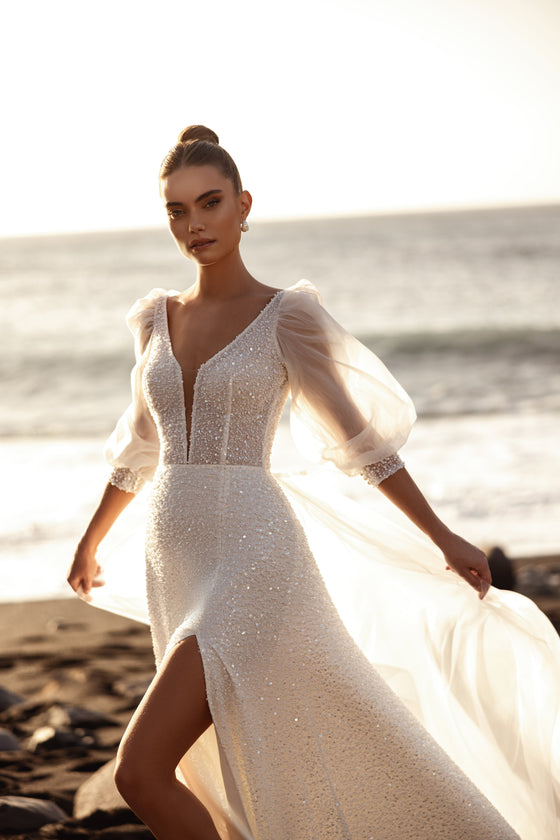 Robe de mariée Davina, avec des manches bouffantes transparentes et des détails scintillants au soleil.