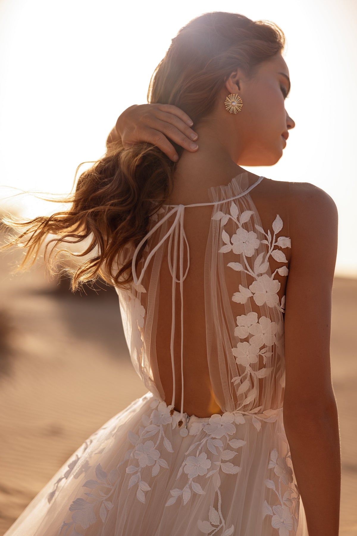 Robe de mariée Ellie, avec un corsage transparent en dentelle florale et une jupe fluide en tulle, dans la lumière du désert.