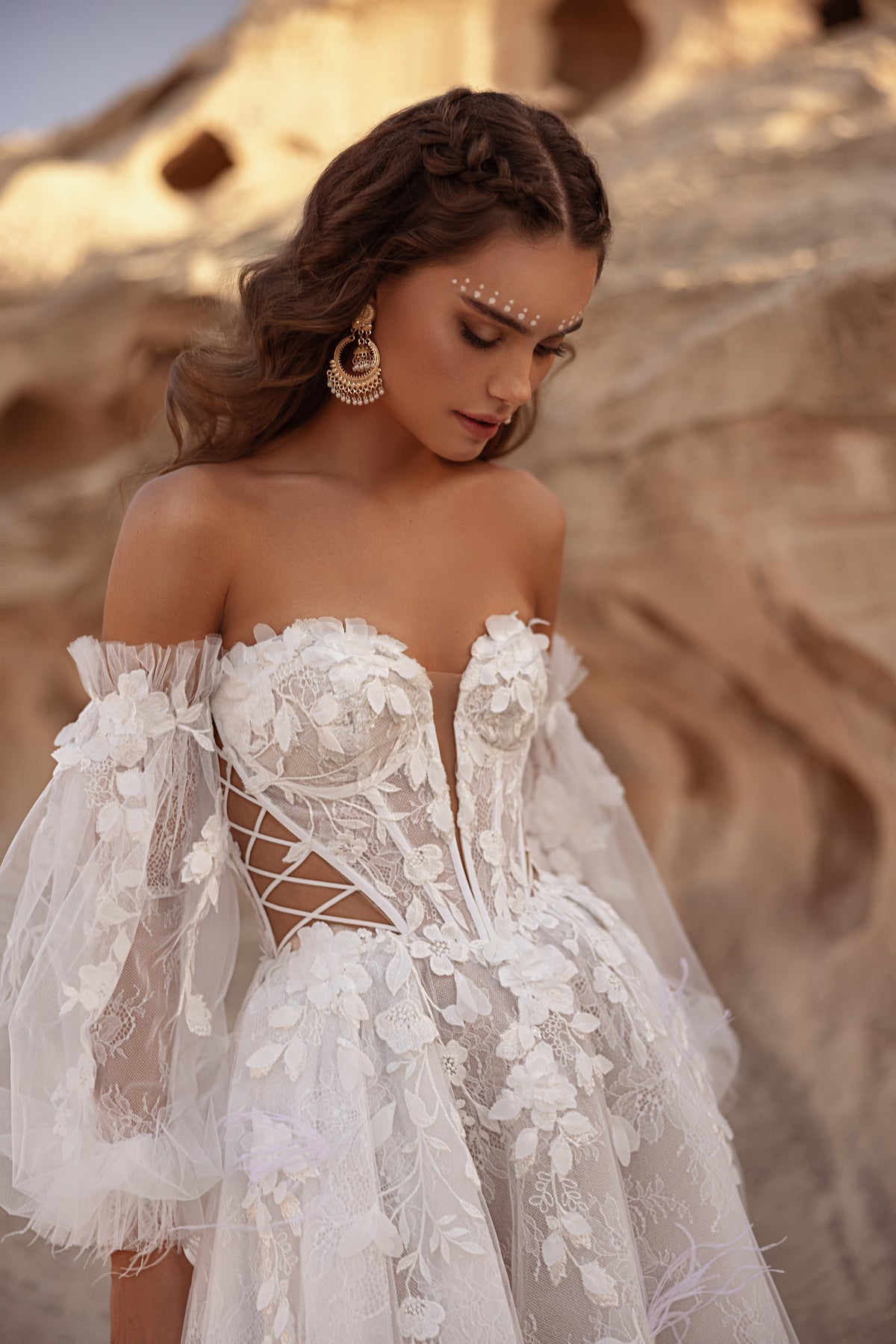 Robe de mariée Huda, avec des manches laissant les épaules dénudées et un corset structuré en dentelle.