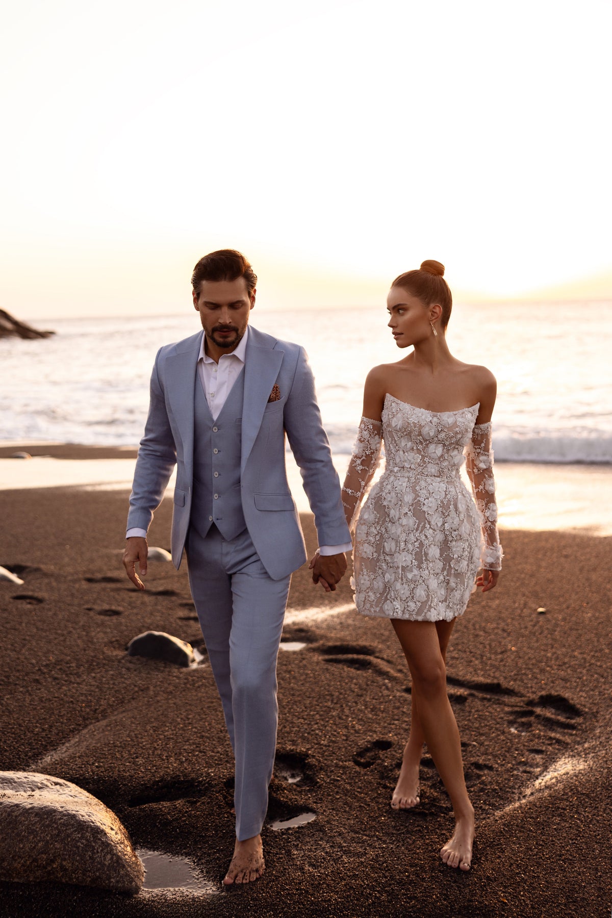 Robe de mariée courte Kayla, avec de longues manches transparentes et des appliqués floraux en relief.