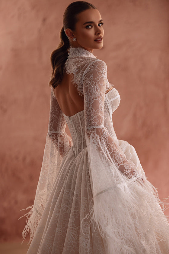 Robe de mariée Michelle en dentelle, avec des manches bordées de plumes et un corset.