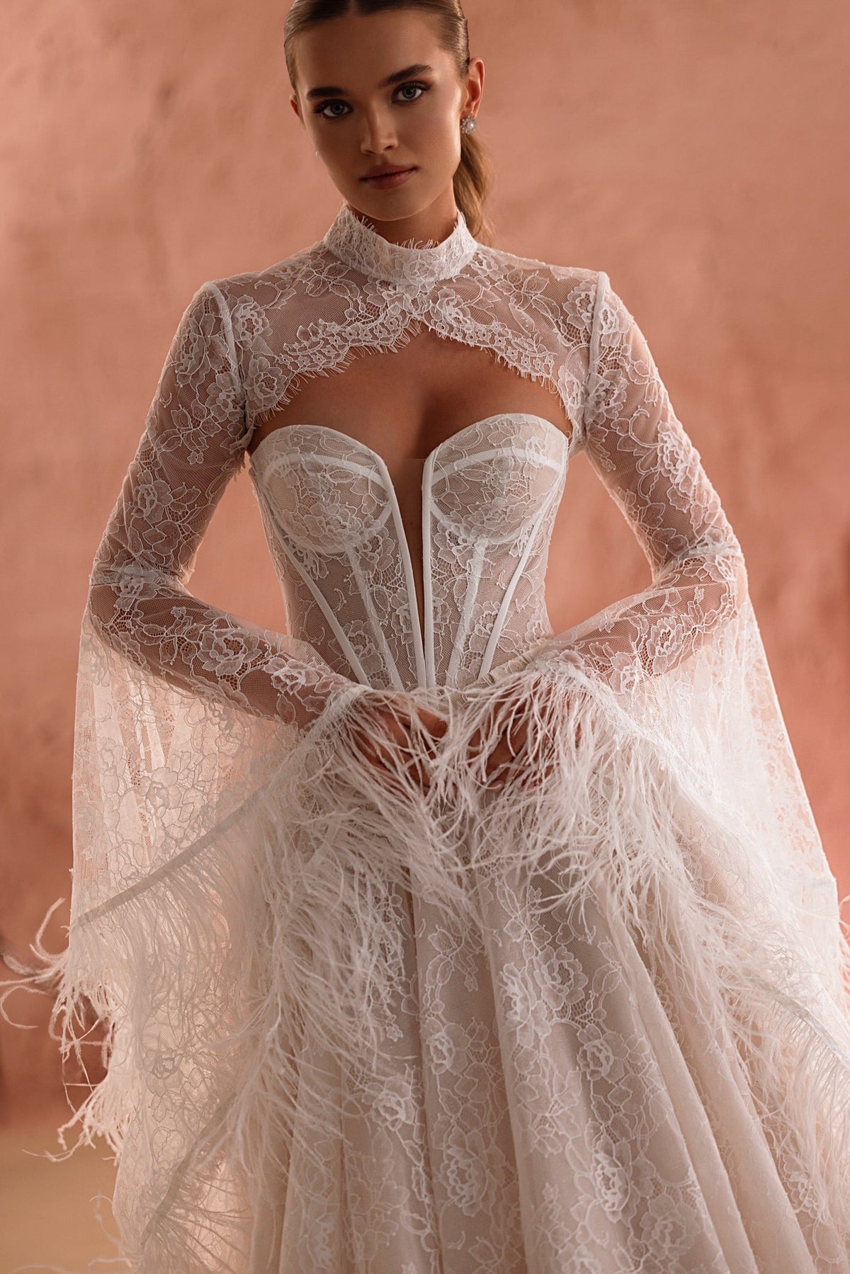 Robe de mariée Michelle, avec un dos ouvert en dentelle et des manches transparentes ornées de plumes.