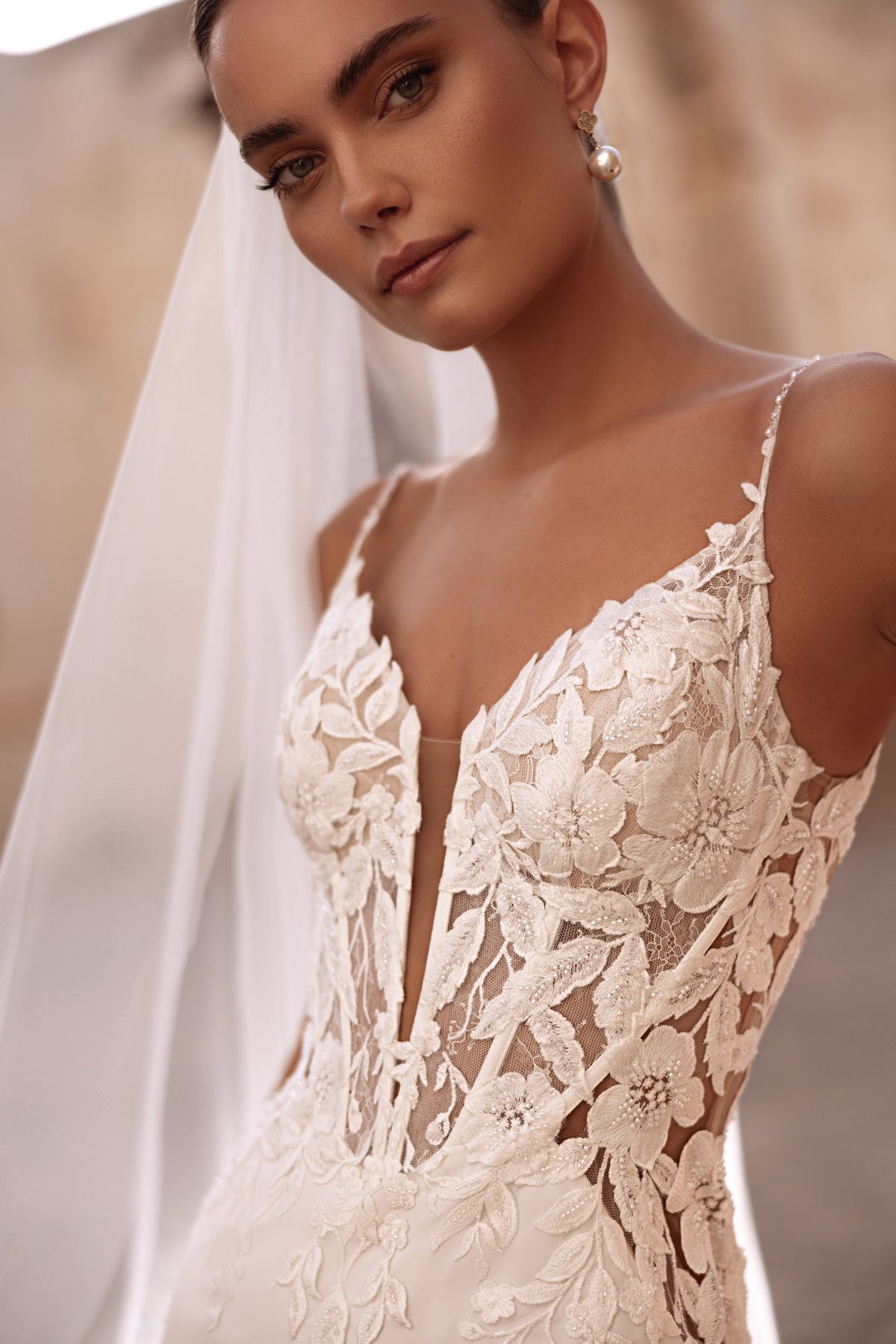 Robe de mariée Munira en dentelle, avec des appliqués floraux en relief et des empiècements transparents.