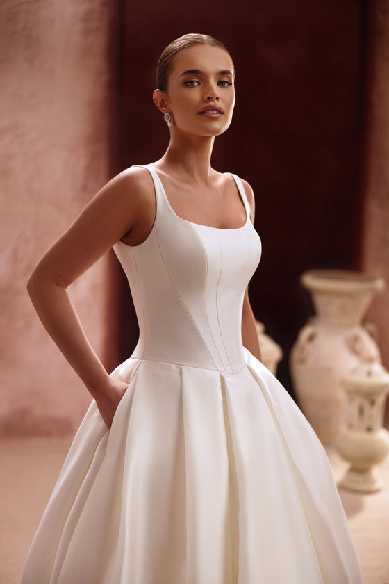 Robe de mariée Nicolette, avec un corsage épuré en satin à bretelles et une volumineuse jupe princesse.