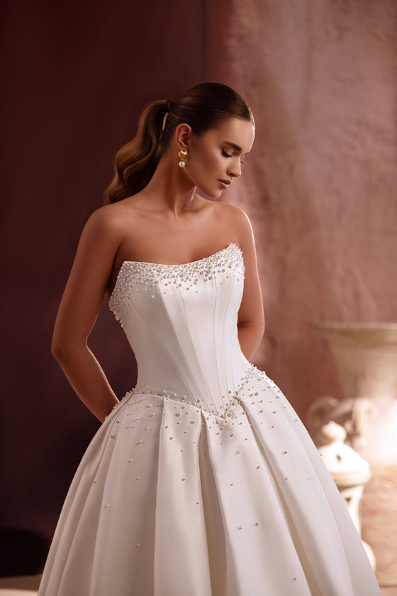 Robe de mariée princesse Noor en satin, avec un corset sans bretelles et des ornements de perles.