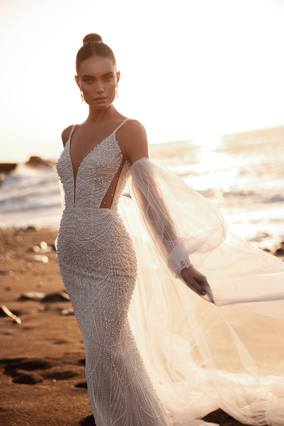 Robe de mariée sirène Rebecca, avec de fines bretelles et des broderies de perles au coucher du soleil.