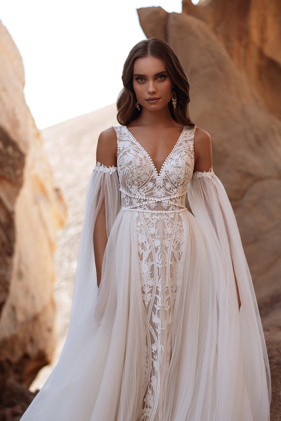 Robe de mariée Salome, avec les épaules dénudées, de longues manches en tulle et des détails de dentelle.