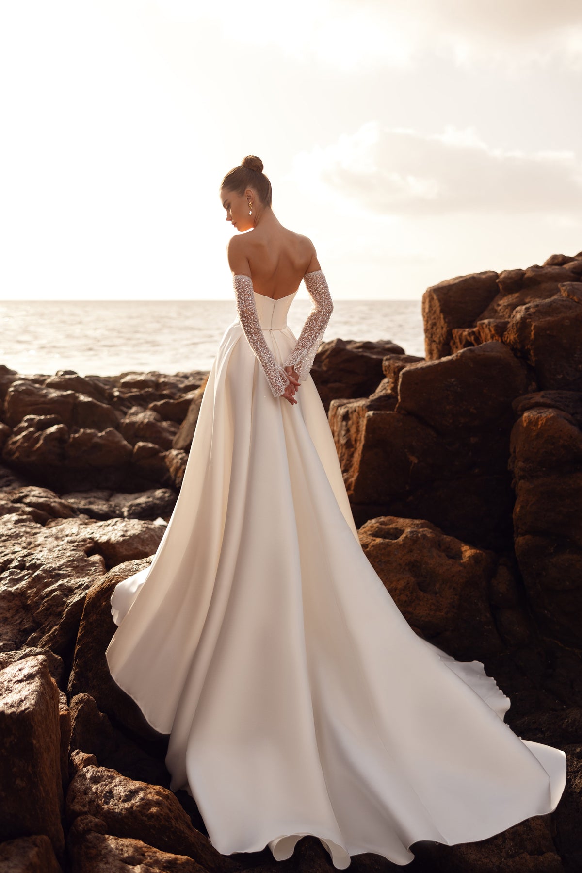Robe de mariée Sarabi sans bretelles, portée avec des gants ornés de perles.